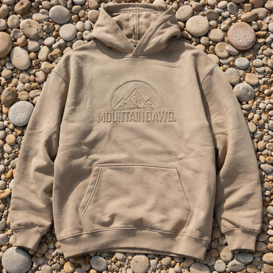 Smoked Pebble hoodie with 'MOUNTAIN DAWG' logo on a pebble surface